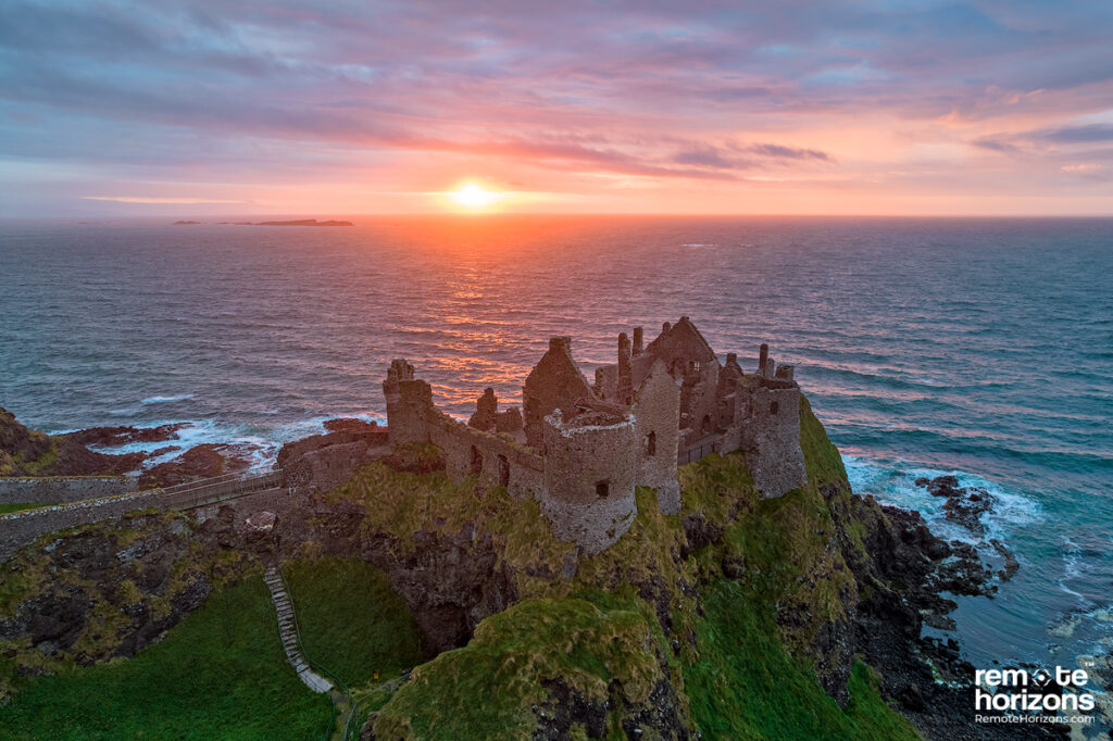 Northern Ireland aerial landscape photograph of Dunluce Castle at sunset with the Skerries near Portrush also visible. 